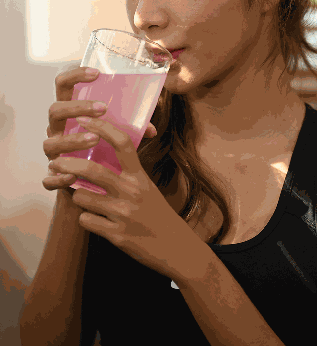 A woman drinking a pink Creatine+ drink