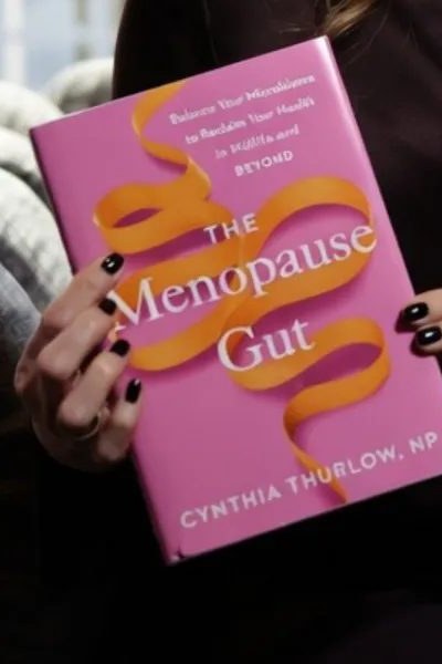 The Menopause Gut book cover, held by Cynthia